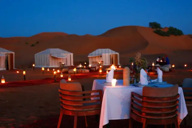 Mesa para dos con faroles encendidos sobre las dunas de Merzouga al anochecer